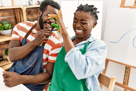 African american painter couple smiling happy painting hands sitting on the table at art studio.