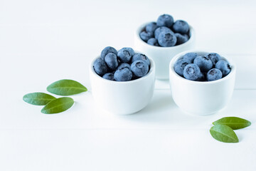 fresh blueberries in white cups on a white background close-up. background with blueberries. blueberries in bowls on the table.