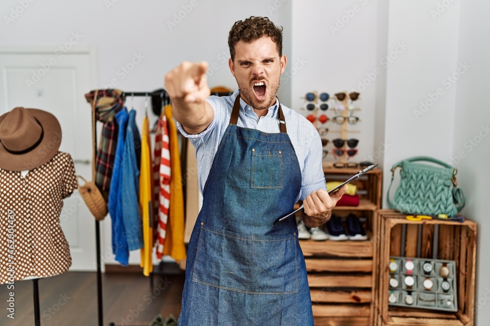 Sticker handsome young man working as manager at retail boutique pointing displeased and frustrated to the c