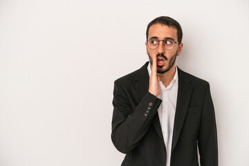 Young caucasian business man isolated on white background is saying a secret hot braking news and looking aside