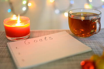 Planning goals for the next year with a Christmas background, a burning candle, a cup of tea and a...