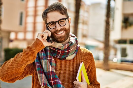 Caucasian man with beard having a conversation speaking on the phone outdoors on a sunny day