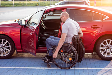 person with a physical disability getting in red car from wheelchair