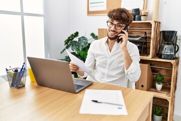 Young arab man talking on the smartphone reading document at office