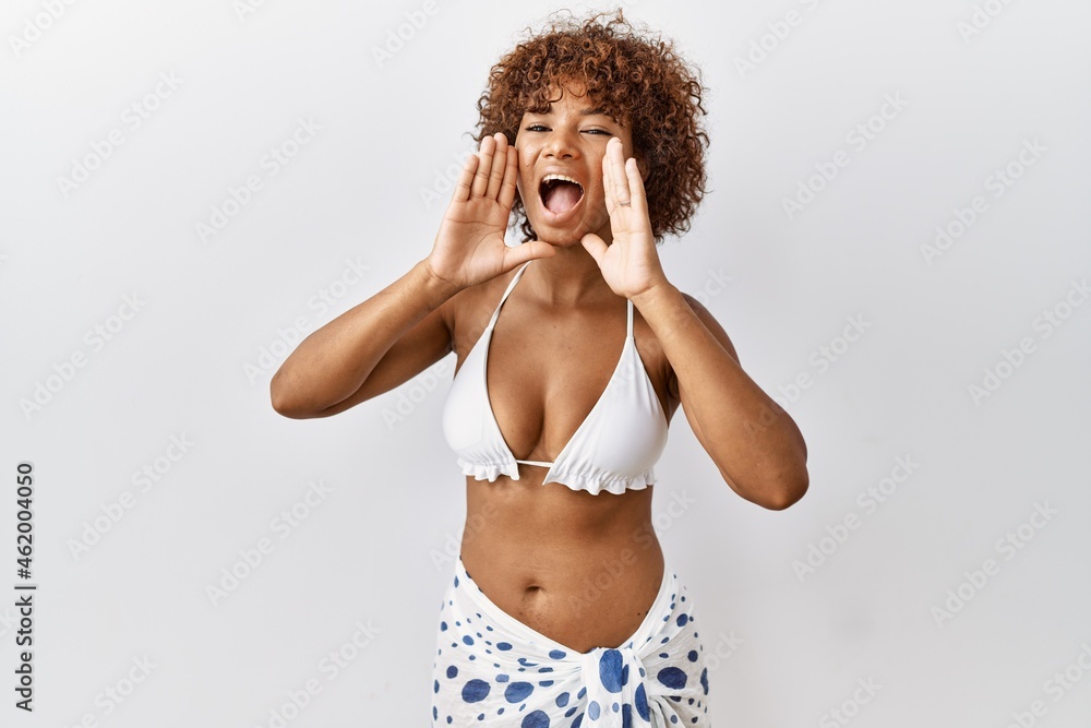 Poster Young african american woman with curly hair wearing bikini smiling cheerful playing peek a boo with hands showing face. surprised and exited