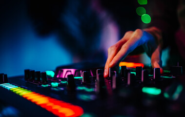 DJ Hands creating and regulating music on dj console mixer in concert nightclub