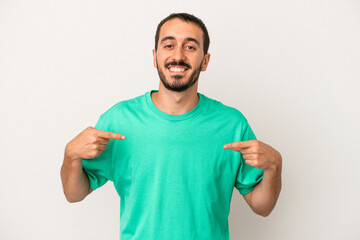 Young caucasian man isolated on white background person pointing by hand to a shirt copy space, proud and confident