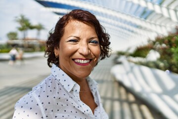 Middle age latin woman smiling happy standing at the city.