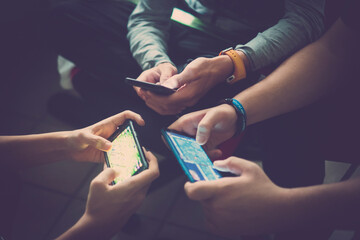 Close up of hands of three teenager friends addicted to technology playing with smartphones...