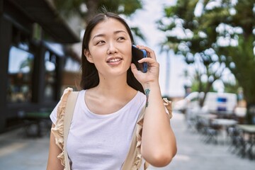 Young chinese girl smiling happy talking on the smartphone at the city.