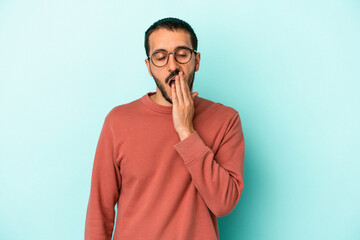 Young caucasian man isolated on blue background yawning showing a tired gesture covering mouth with hand.