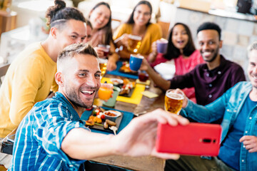 Happy multiracial friends taking a group selfie at restaurant - Young millenial people laughing...