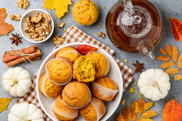 Obraz na płótnie Canvas Spicy pumpkin muffins or cupcakes with walnuts in a white plate. Autumn bakery concept. Tea party . Teapot of black tea. Top view