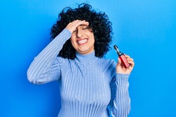 Young middle east woman holding electronic cigarette stressed and frustrated with hand on head,...