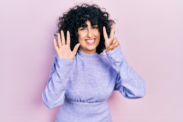 Young middle east woman wearing casual clothes showing and pointing up with fingers number seven while smiling confident and happy.