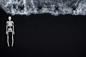 White skeletons, spiders and web on a black background. The concept of the Day of the Dead. Happy Halloween. A postcard for All Saints' Day. Gloomy background.