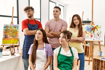 Group of five hispanic artists at art studio smiling looking to the side and staring away thinking.