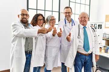 Group of middle age doctor smiling happy doing ok sign with thumbs up in a medical meeting at the clinic office.