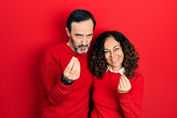 Fototapeta premium Middle age couple of hispanic woman and man hugging and standing together doing money gesture with hands, asking for salary payment, millionaire business