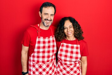 Middle age couple of hispanic woman and man wearing cook apron with a happy and cool smile on face. lucky person.