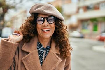 Middle age hispanic woman smiling happy shopping at the city.