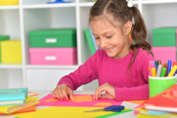 Porait of cute little girl is cutting paper