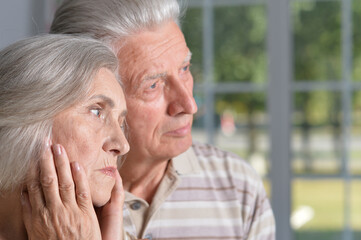 Portrait of sad senior couple posing at home