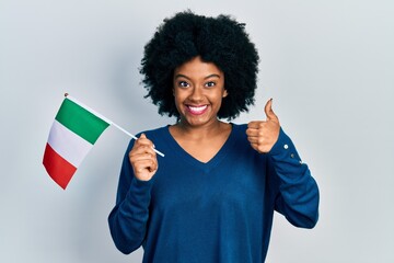 Young african american woman holding italy flag smiling happy and positive, thumb up doing excellent and approval sign