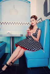 Retro (vintage) portrait of smiling beautiful young woman sitting in cafe and drinking beverage....