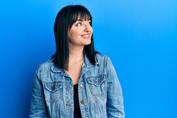 Young hispanic woman wearing casual denim jacket looking to side, relax profile pose with natural face and confident smile.