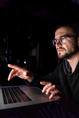 A man with glasses works at a computer late at night.