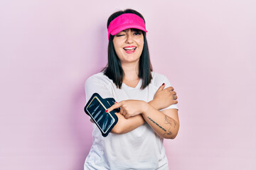 Young hispanic woman wearing sportswear winking looking at the camera with sexy expression,...