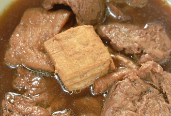 boiled tofu and textured vegetable protein vegetarian food in herb brown soup on bowl