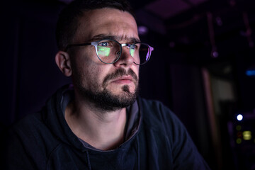 A man stares intently at a computer screen in the dark at night.