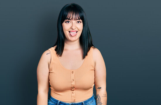 Young hispanic plus size woman wearing casual clothes sticking tongue out happy with funny expression. emotion concept.
