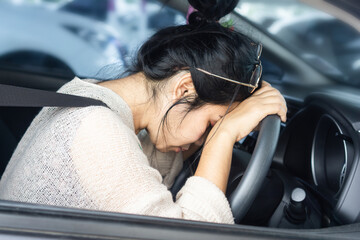 Asian woman fall asleep on the steering wheel in the car, safety first stop at the car park tired...