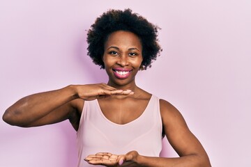 Young african american woman wearing casual sleeveless t shirt gesturing with hands showing big and...
