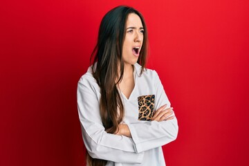 Young hispanic girl with arms crossed gesture angry and mad screaming frustrated and furious,...