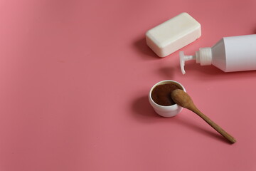 Spa composition with scrub, means with dispenser and soap on a pink background.