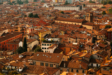 Fototapeta na wymiar Aerial view of the historical center of Brescia (Lombardy, Italy) with red tile roofs, chimneys, cathedral's domes and tall white brick old towers. Traditional European medieval architecture.