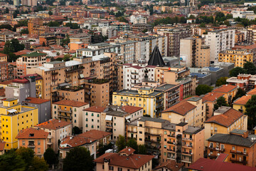 Fototapeta na wymiar Aerial view of the modern centre of Brescia (Lombardy, Italy) with tiled red roofs, chimneys, cathedral's domes and tall white brick old towers. Traditional Italian buildings architecture in Europe