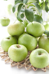 Juicy green apples on a white table with wicker stand