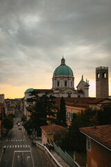 Fototapeta na wymiar The turquoise dome with stone white sculptures and the tower of the central Catholic church (Duomo Vecchio Cathedral) at sunset in Brescia, Lombardy, Italy. Panoramic view. Italian architecture