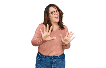 Young plus size woman wearing casual clothes and glasses afraid and terrified with fear expression stop gesture with hands, shouting in shock. panic concept.