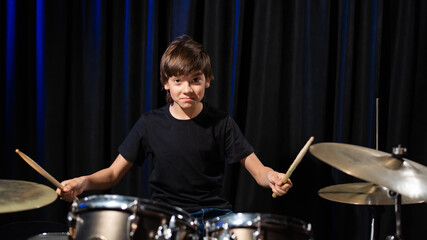 A boy plays drums in a recording studio
