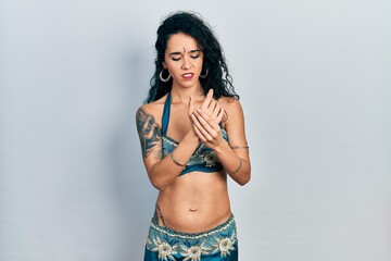 Young woman wearing bindi and traditional belly dance clothes suffering pain on hands and fingers, arthritis inflammation