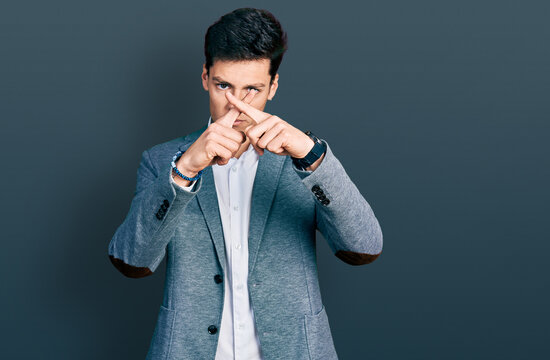 Young hispanic man wearing business clothes rejection expression crossing fingers doing negative sign