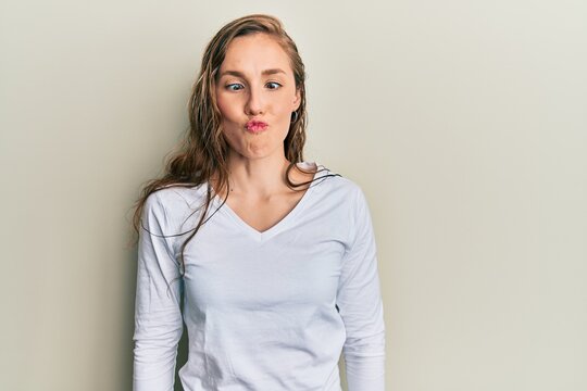 Young blonde woman wearing casual clothes making fish face with lips, crazy and comical gesture. funny expression.