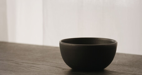 Black empty ceramic bowl on black wood table
