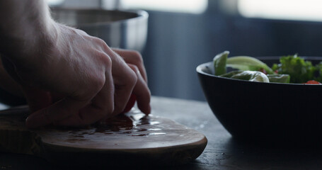 man making salad in black bowl closeup